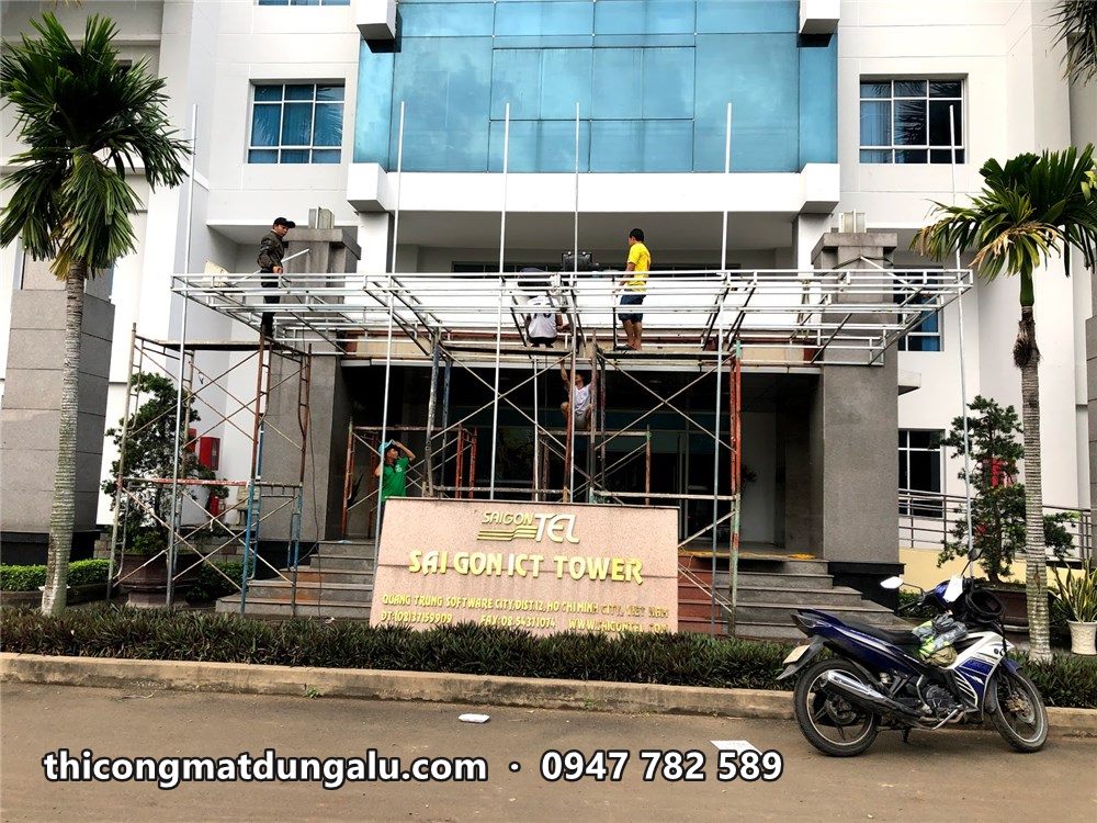 Saigon ICT Tower với mảng kính xanh, giàn giáo trước lối vào chính