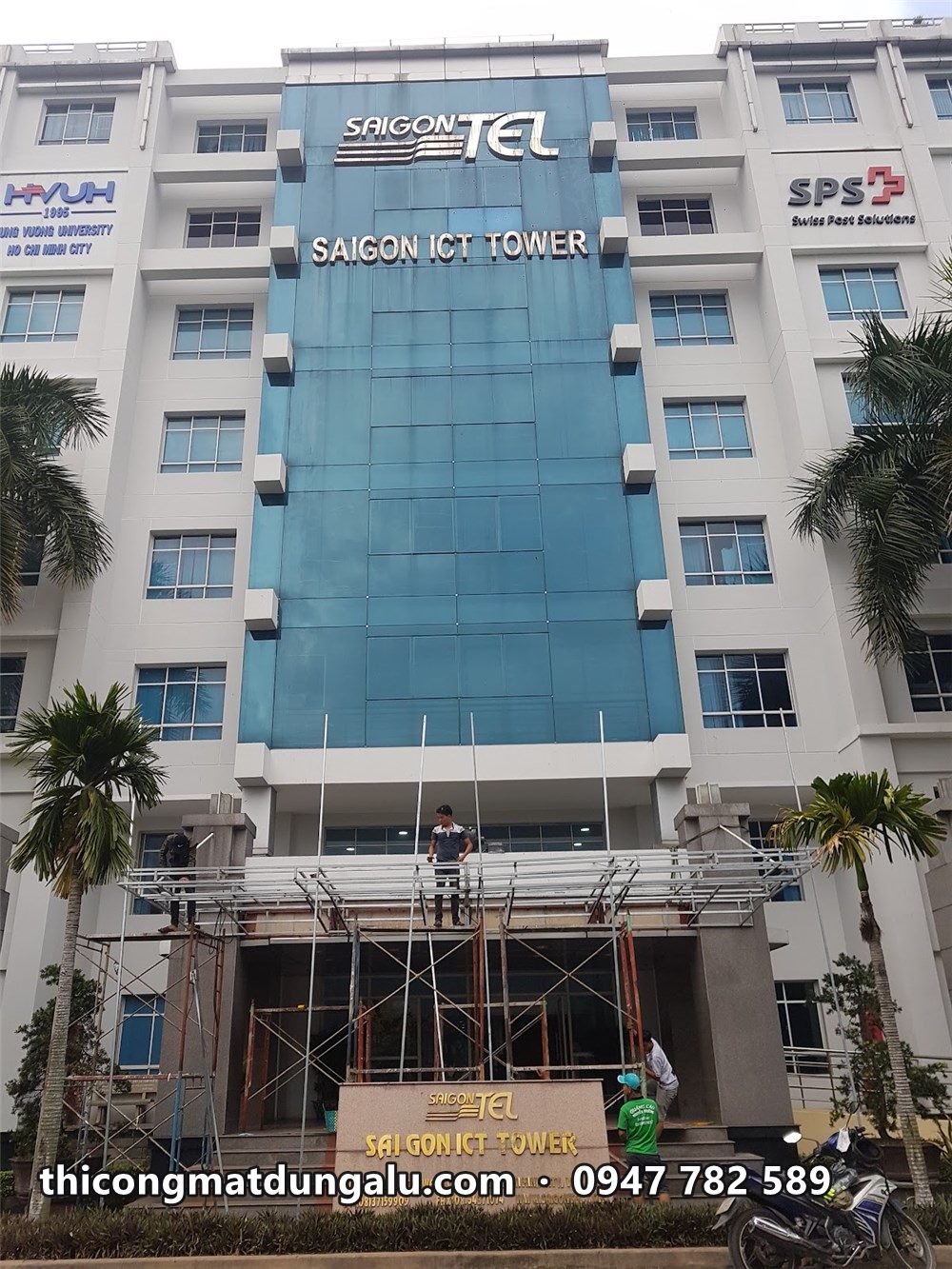 Mặt tiền Saigon ICT Tower với dải kính xanh, thợ đang làm ở mái sảnh