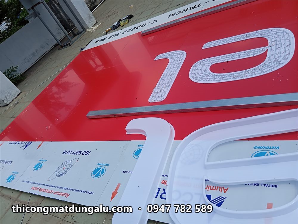 Cận cảnh chữ el trắng đã gắn trên mặt alu đỏ, màng bảo vệ chưa bóc