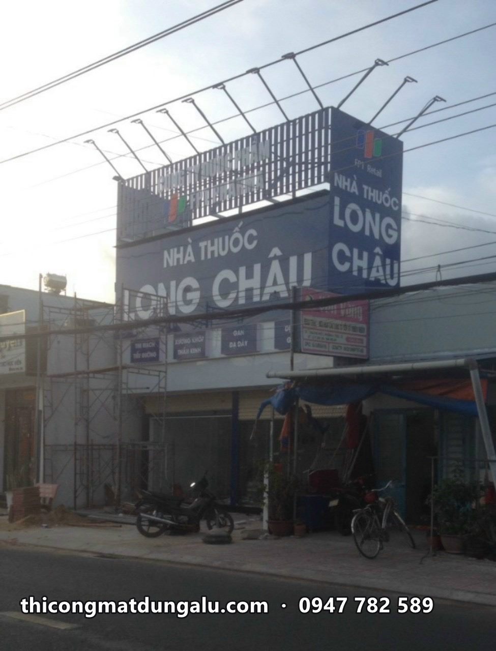 Nhà thuốc Long Châu góc đường với biển ngang và biển dọc góc nhà đang lắp, giàn giáo trên mái