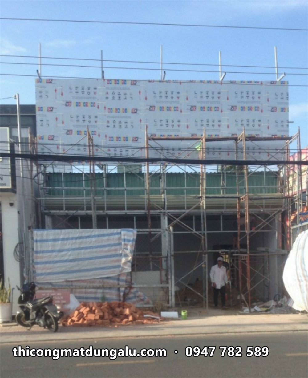 Khung mặt dựng phủ tấm alu còn dán màng trên nhà phố hai tầng, giàn giáo phía trước