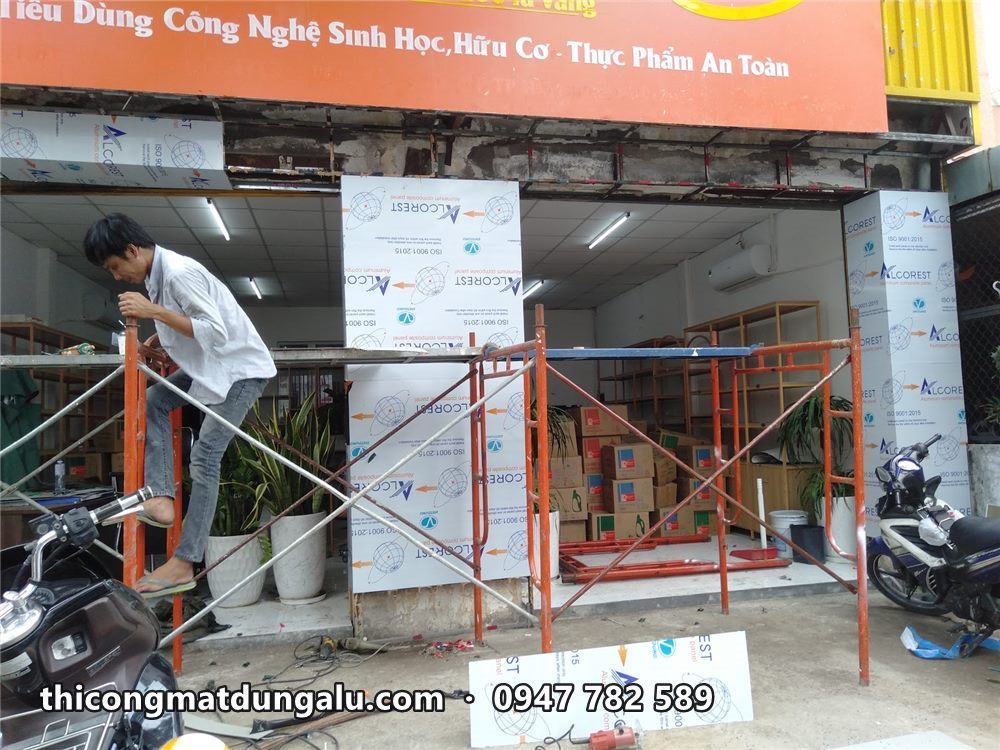 Thợ trên giàn giáo ốp alu khung cửa siêu thị mini