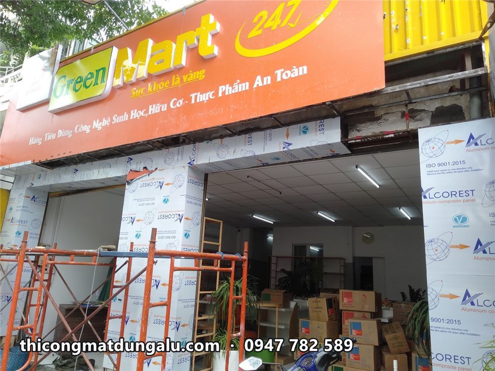 Mặt tiền Green Mart 247 với trụ alu đang hoàn thiện, giàn giáo cam phía trước