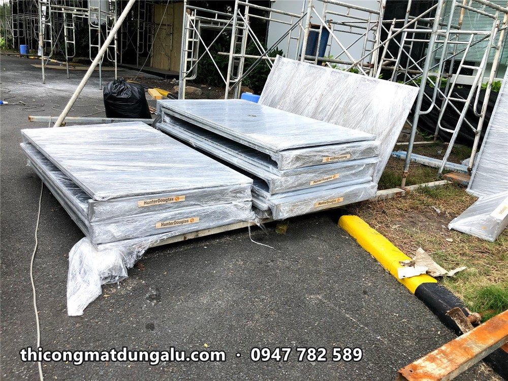 Tấm alu xếp chồng trên pallet cạnh giàn giáo, còn màng bảo vệ