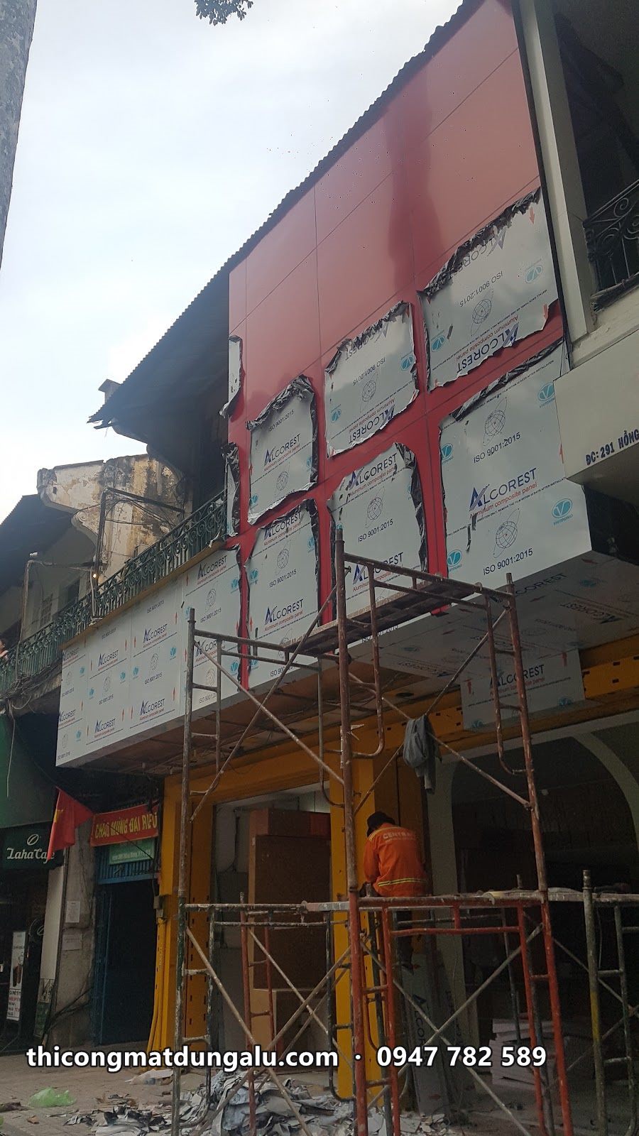 Giàn giáo dựng trước nhà, khung sắt bọc mặt tiền đã ốp một phần alu đỏ