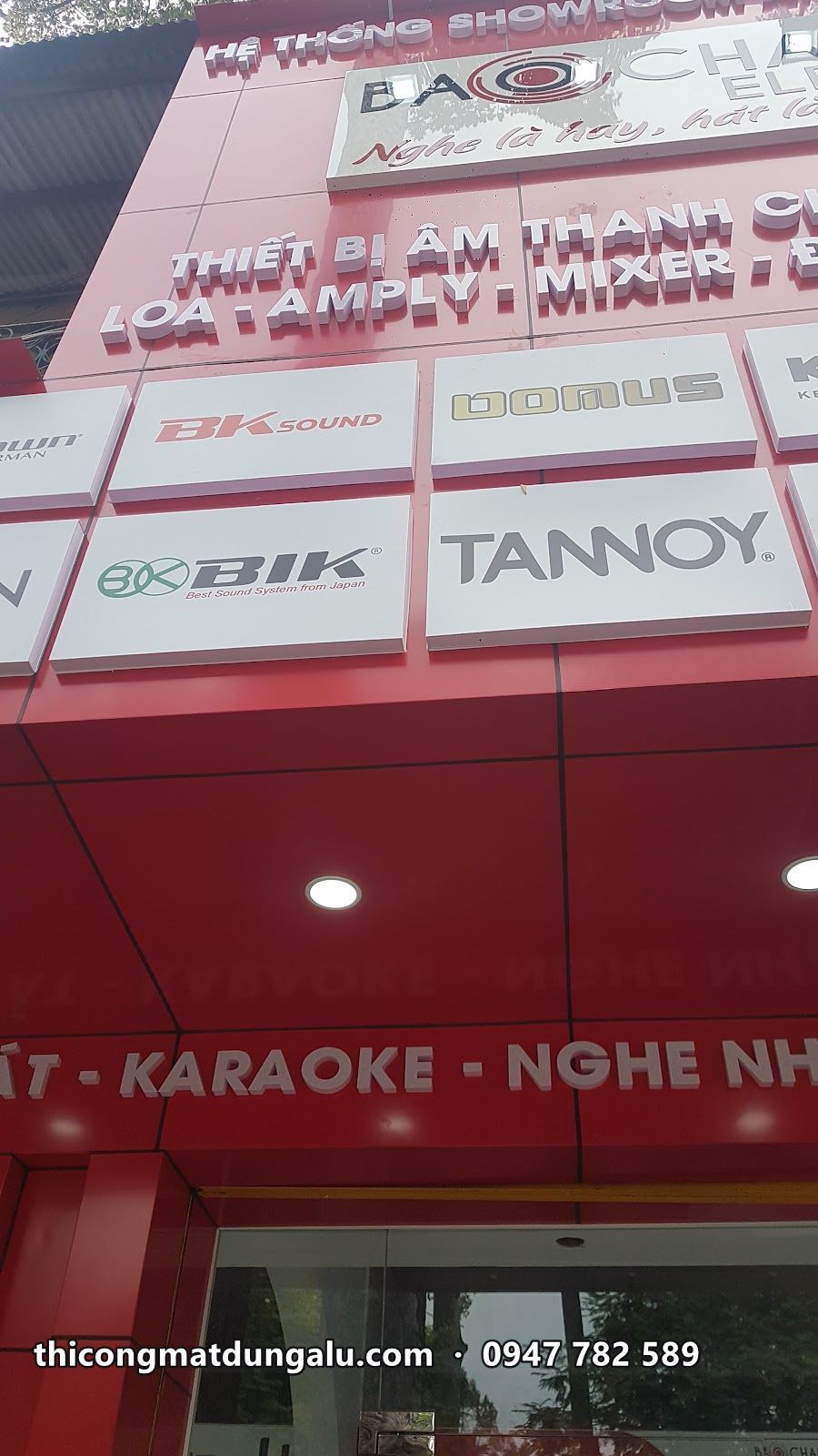 Cận cảnh dãy logo hãng BIK, Tannoy trên nền trắng của mặt dựng đỏ