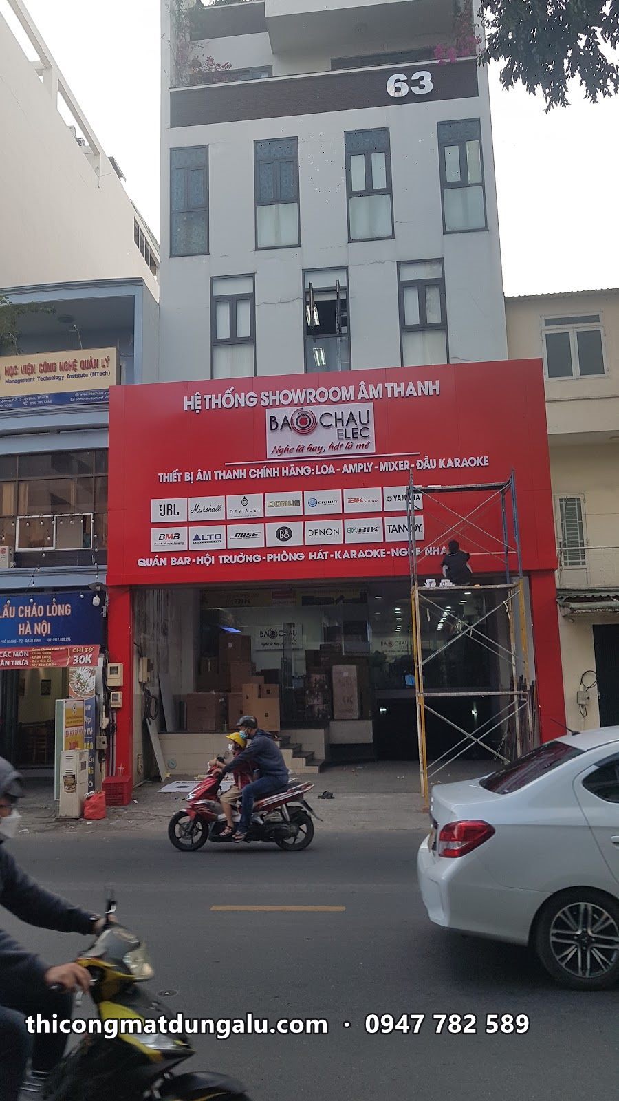 Mặt dựng đỏ showroom âm thanh hoàn thiện dưới tòa nhà, xe máy chạy qua