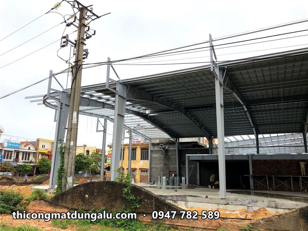Khung thép mái showroom còn trơ, chưa có lớp hoàn thiện, nhìn từ ngoài đường