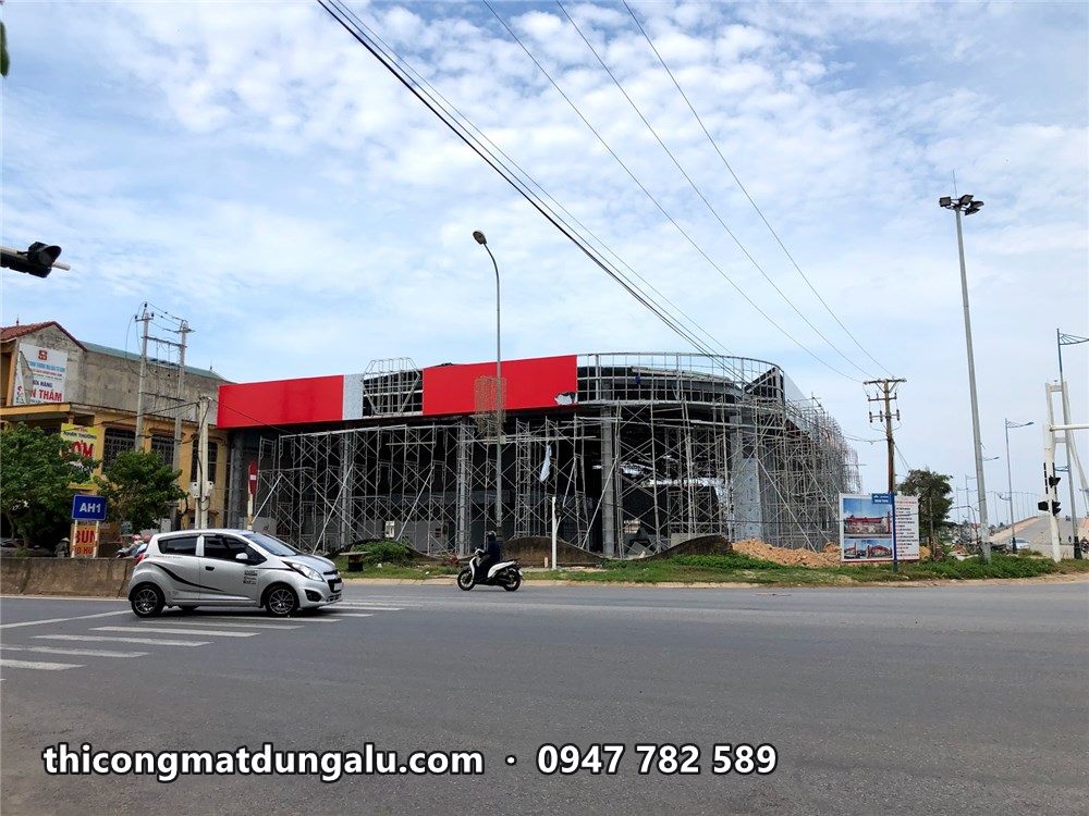 Showroom nhìn từ ngã tư, dải đỏ đã lên một phần, giàn giáo bao quanh
