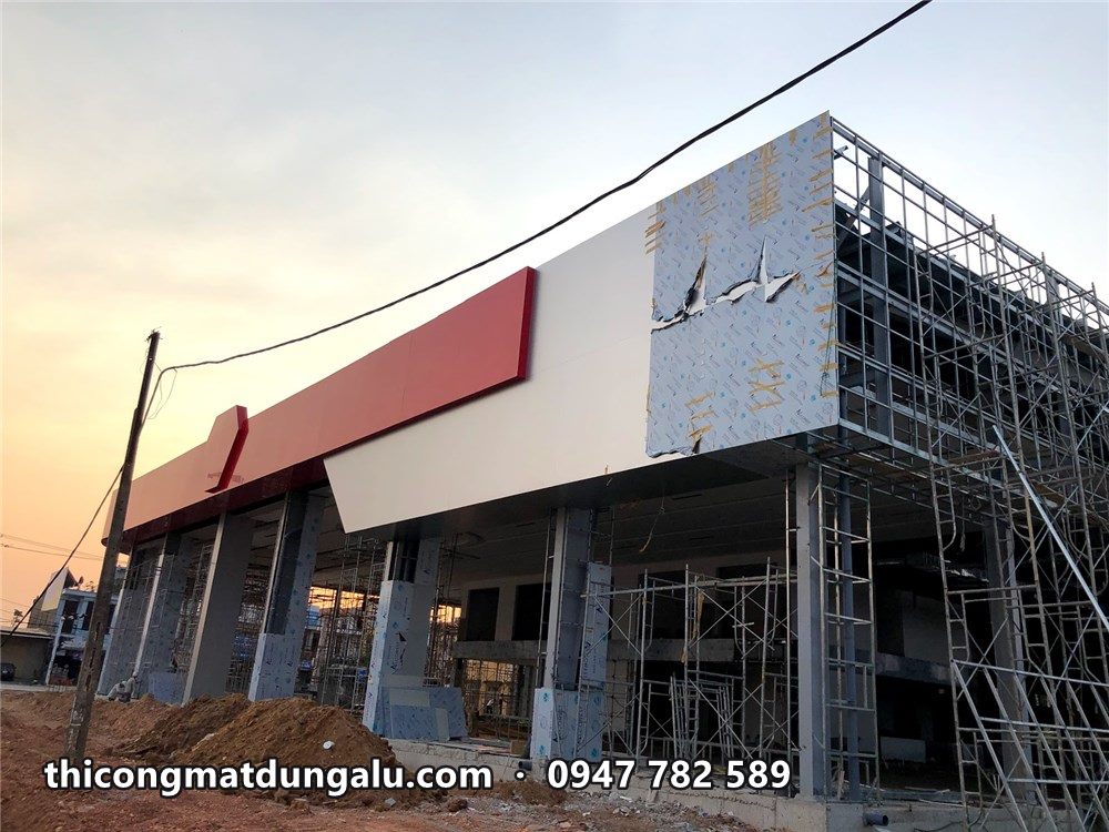 Khối hộp trắng góc showroom đang ốp alu, dải đỏ chạy ngang phía trên