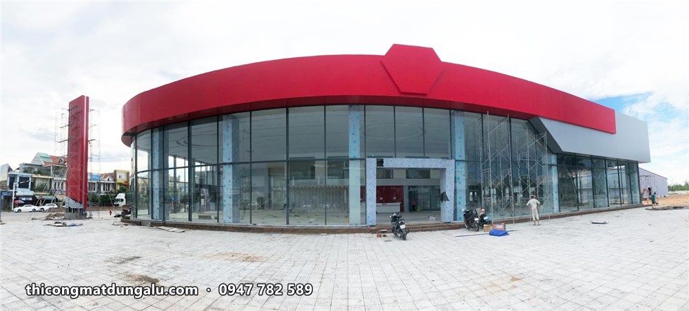 Mặt tiền cong showroom VinFast hoàn thiện, kính trong suốt, dải đỏ phía trên