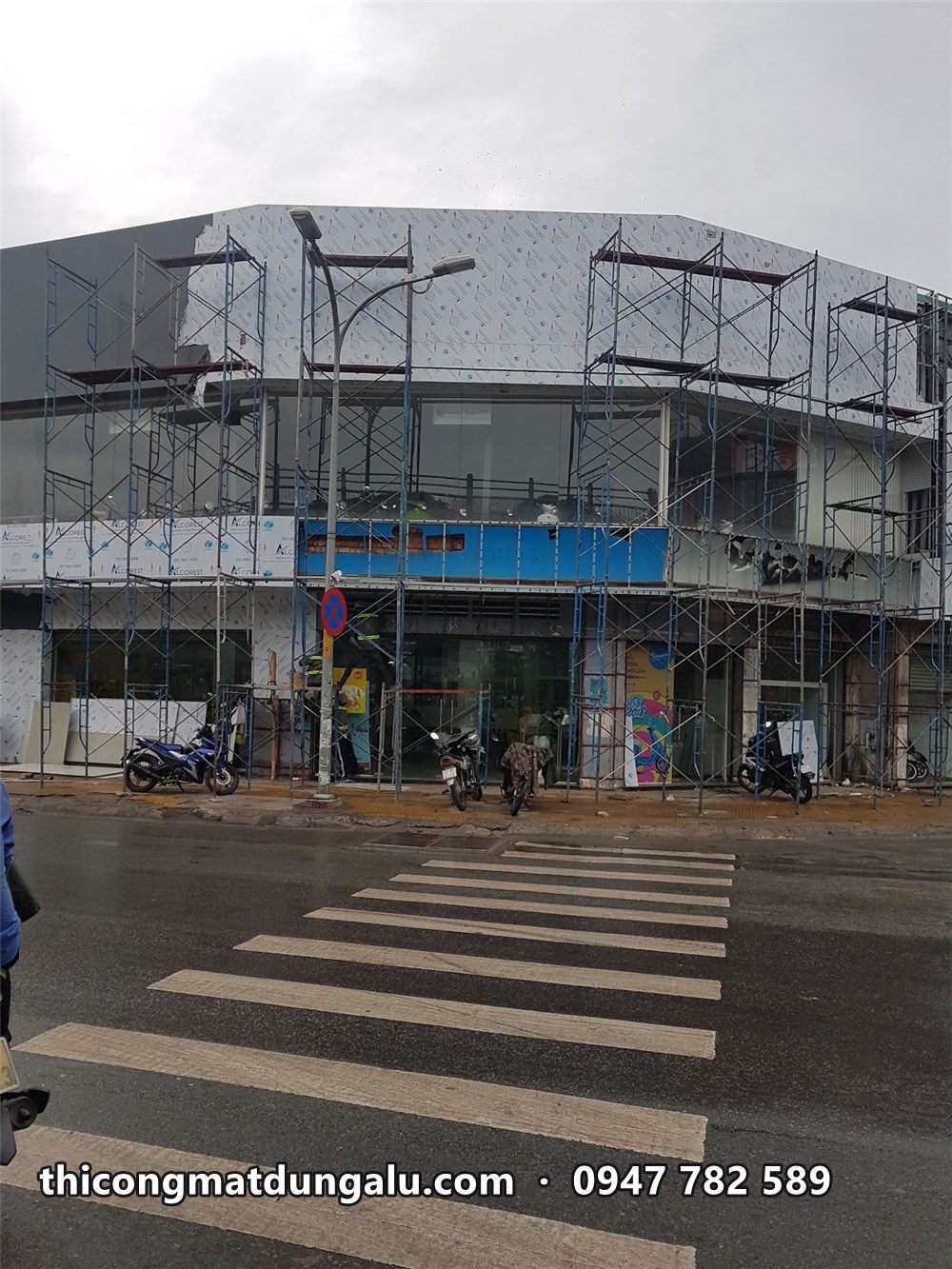Giàn giáo dọc mặt tiền showroom góc đường, vạch kẻ đường phía trước