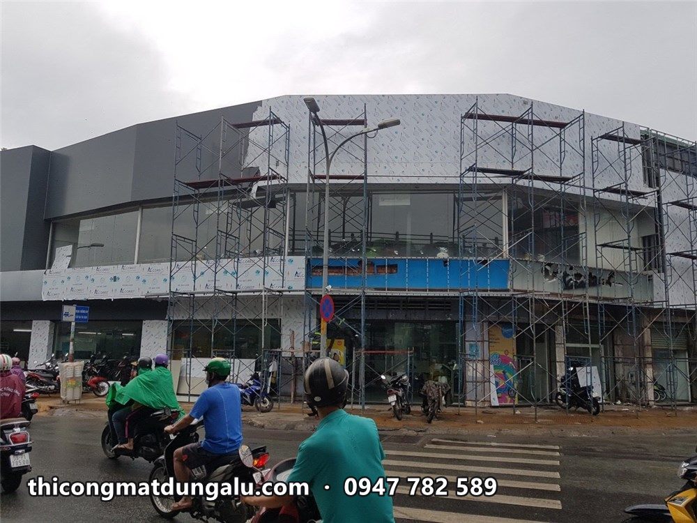 Showroom góc đường nhìn từ bên kia ngã tư, giàn giáo chạy quanh góc bo