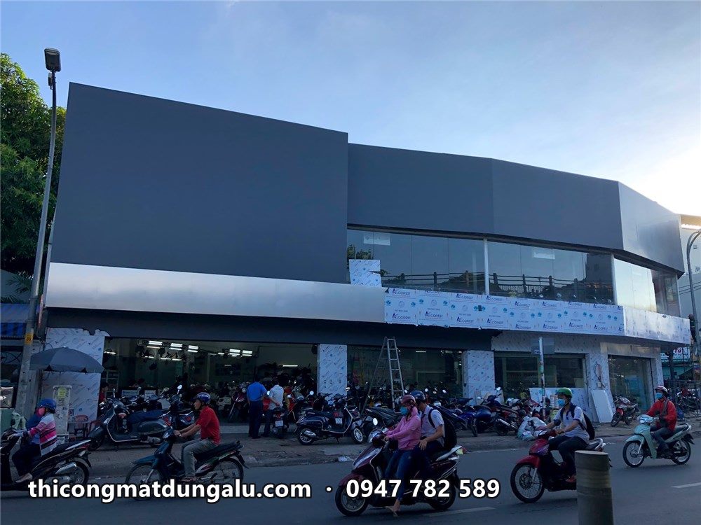 Mặt dựng alu xám showroom lúc chiều, xe máy đậu kín vỉa hè