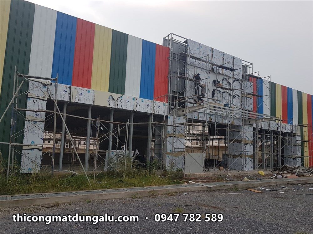 Mặt tiền dài trung tâm thương mại với dải sọc màu chạy ngang tầng trên và khối sảnh đang ốp