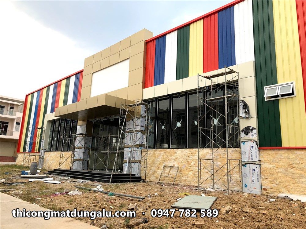 Khối sảnh vào ốp alu kem nằm giữa mặt dựng sọc màu, còn vài tấm chưa bóc màng