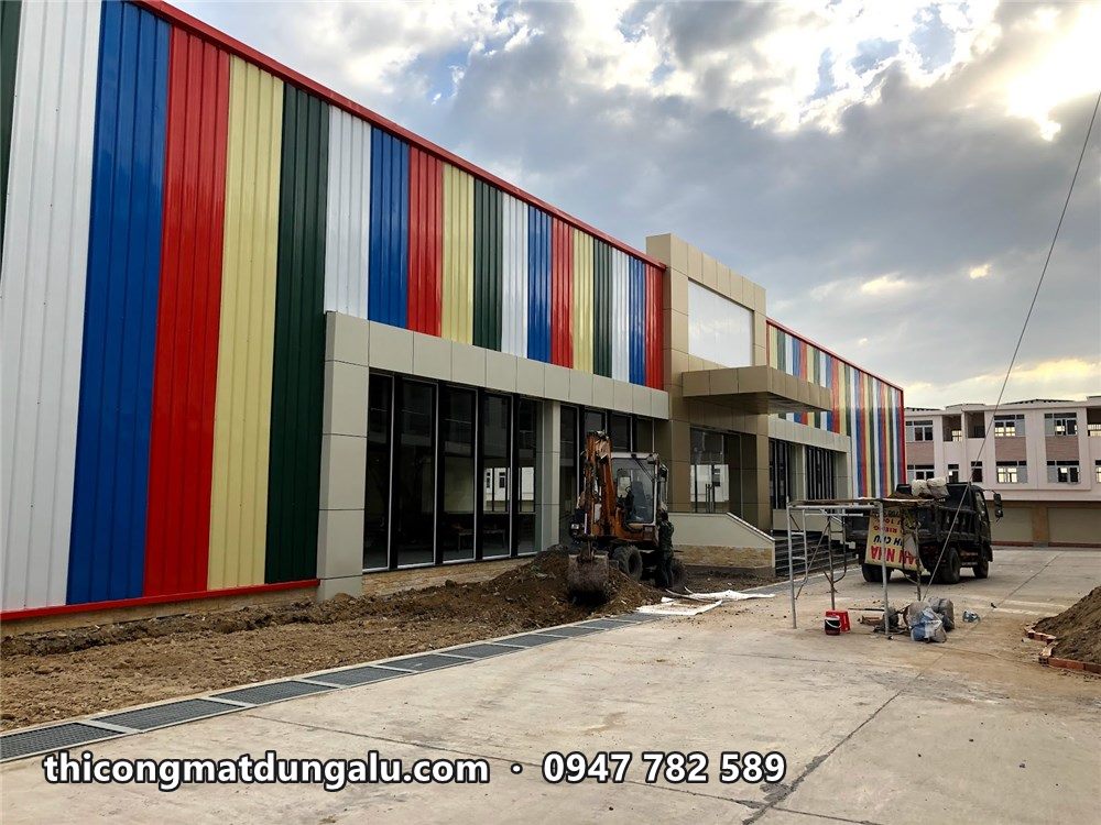 Mặt dựng sọc màu nhìn dọc theo vỉa hè, thợ đang dọn công trường