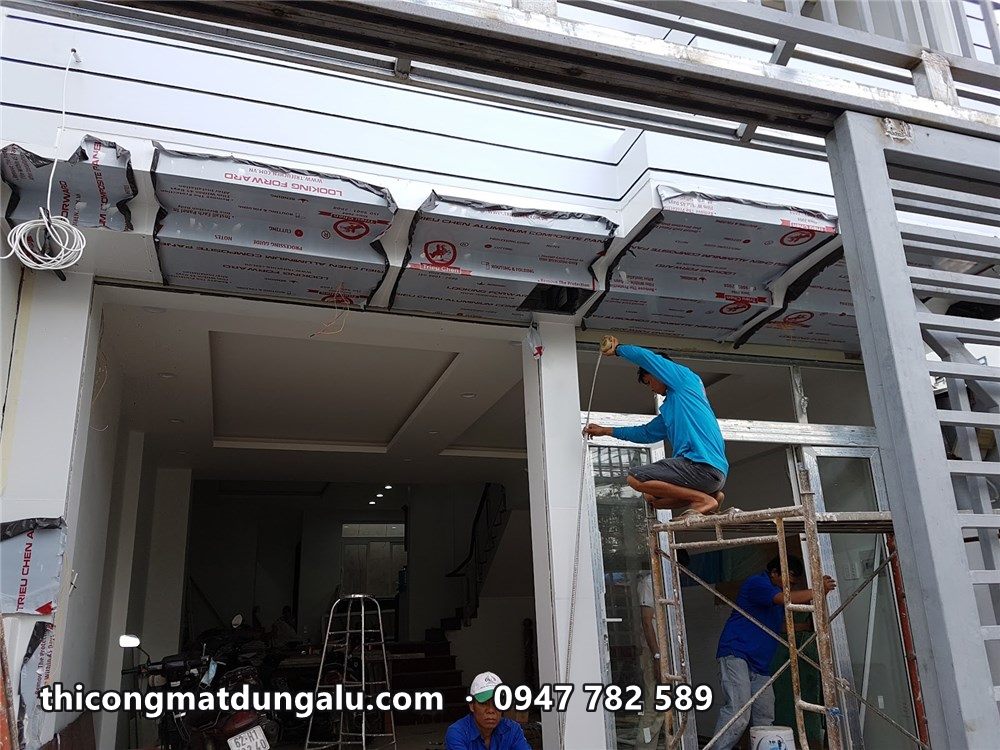 Thợ ốp trần hiên và khung mặt tiền bưu cục, tấm alu còn màng