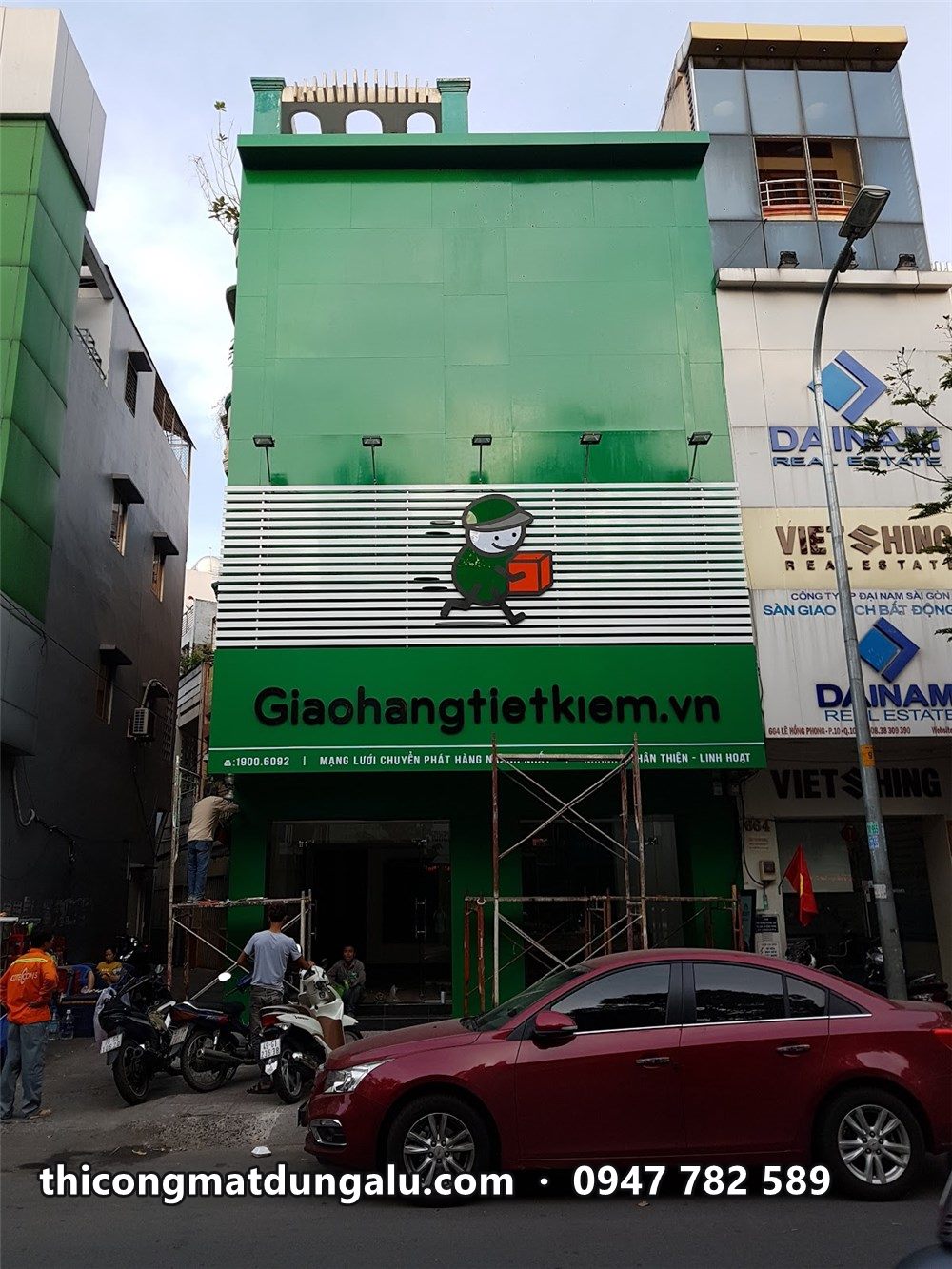 Bưu cục ba tầng hoàn thiện nhìn chéo, ô tô đỏ đậu phía trước