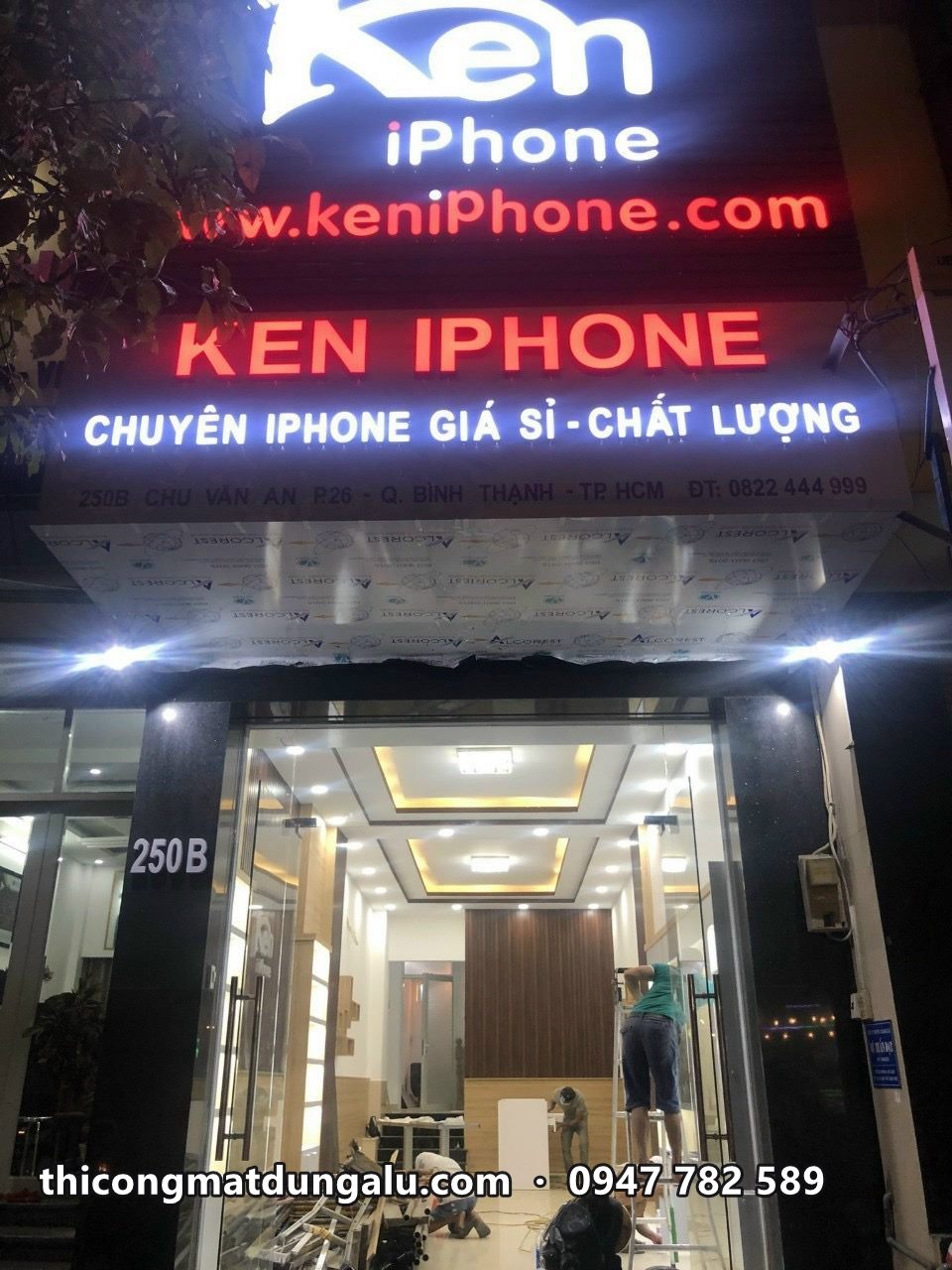 Mặt tiền Ken iPhone ban đêm với nhiều tầng chữ sáng trắng và đỏ