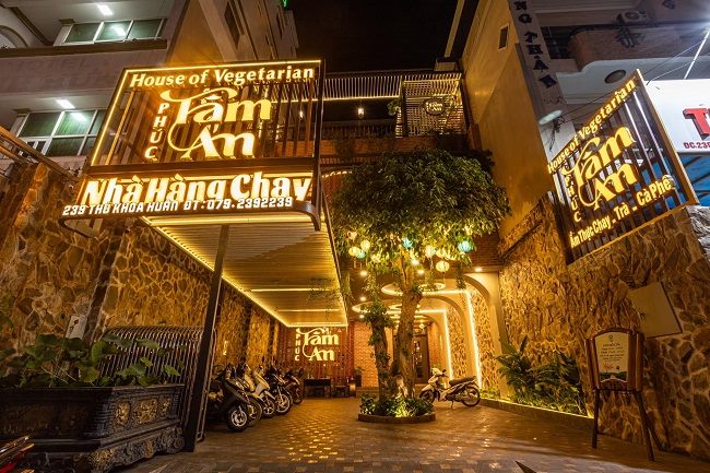 Nhà hàng chay về đêm, chữ nổi vàng hắt sáng giữa cây xanh và đèn