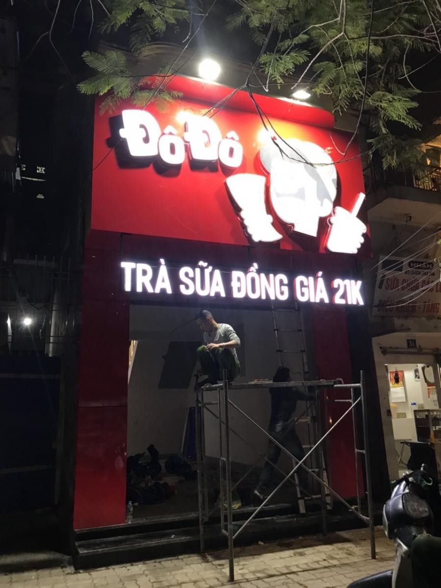 Mặt tiền quán trà sữa ốp đỏ, chữ nổi trắng và logo lớn