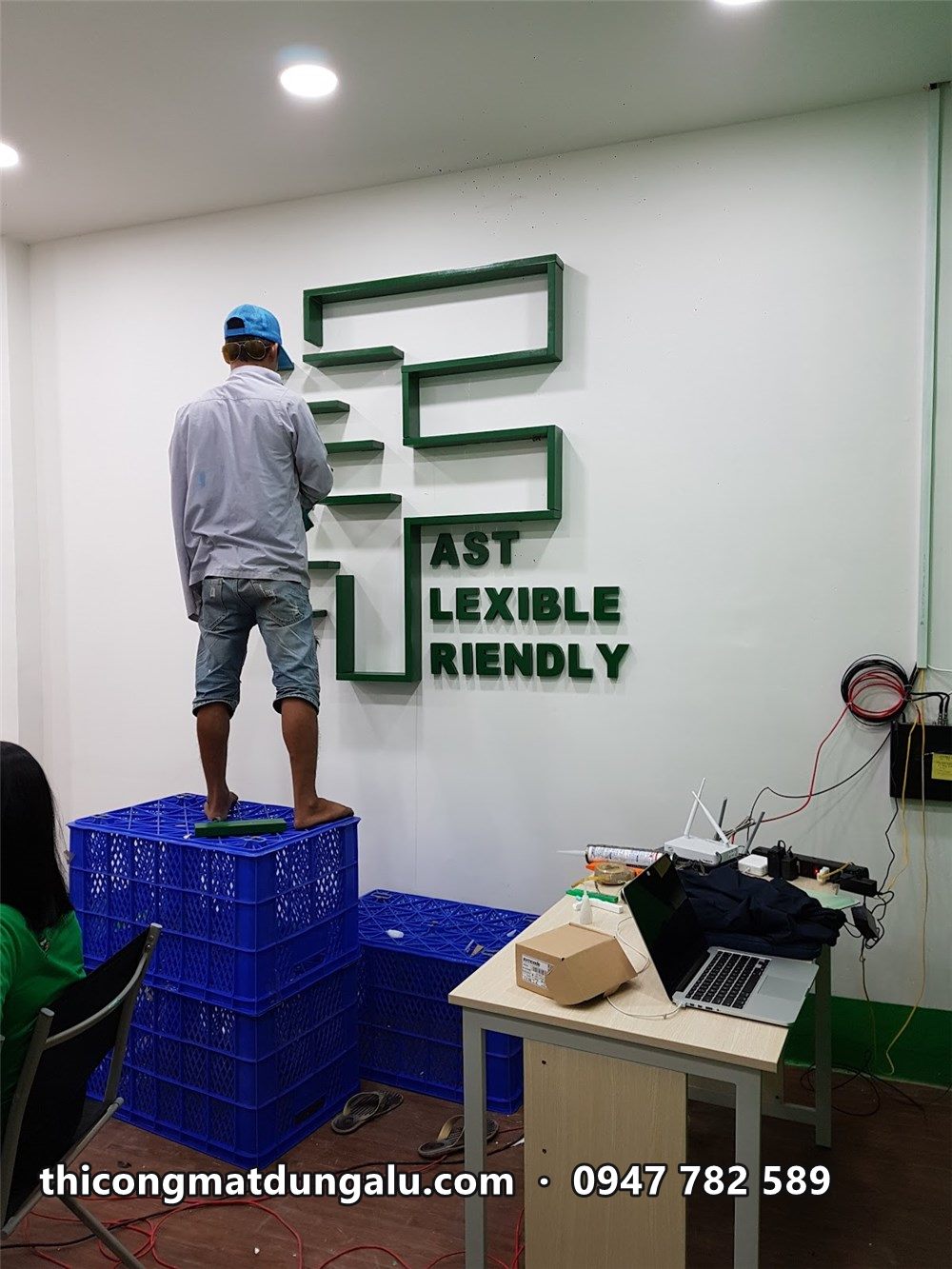 Chữ F xanh với các dòng Fast Flexible Friendly đang hoàn thiện, thợ trên thùng nhựa