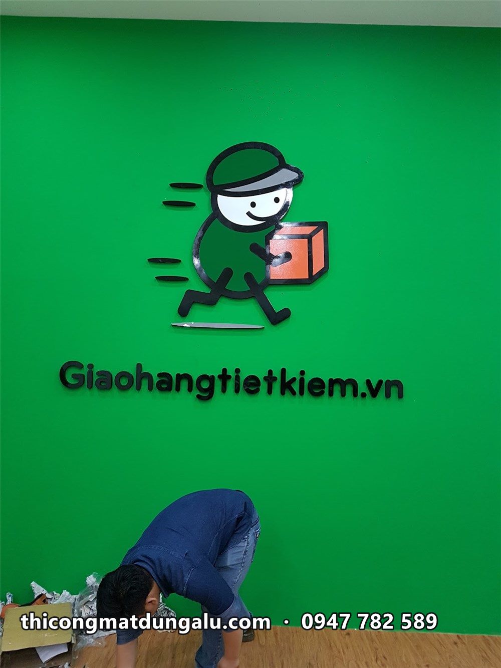 Tường xanh với nhân vật shipper ôm thùng hàng và chữ Giaohangtietkiem.vn