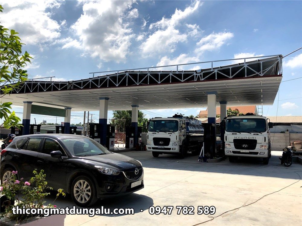 Mái che cây xăng đang thi công, xe bồn và ô tô đậu trong sân