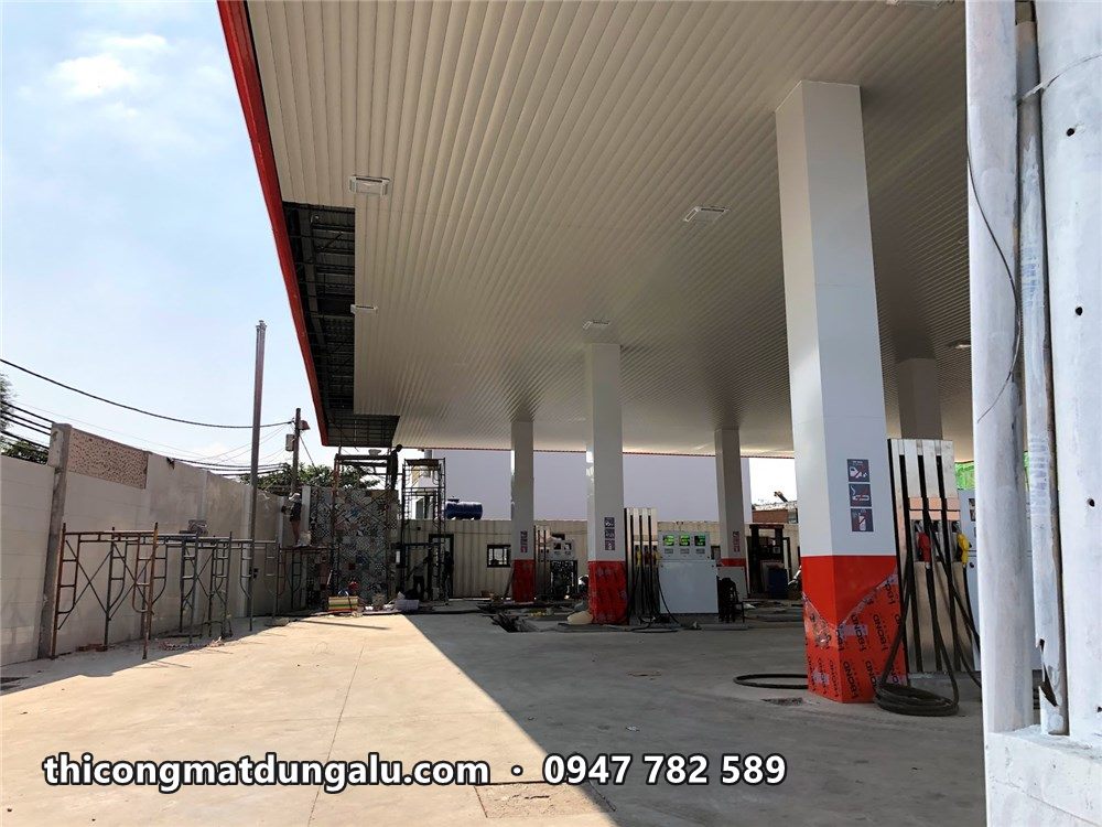 Trần mái che màu trắng và cột bọc trắng chân đỏ tại cửa hàng xăng dầu