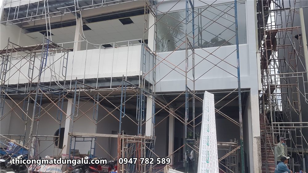 Mặt tiền nhà phố với khung xương và tấm alu xám đang ốp, nhìn từ dưới lên