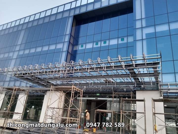 Tòa nhà văn phòng kính xanh với khung thép mái đón sảnh đang lắp