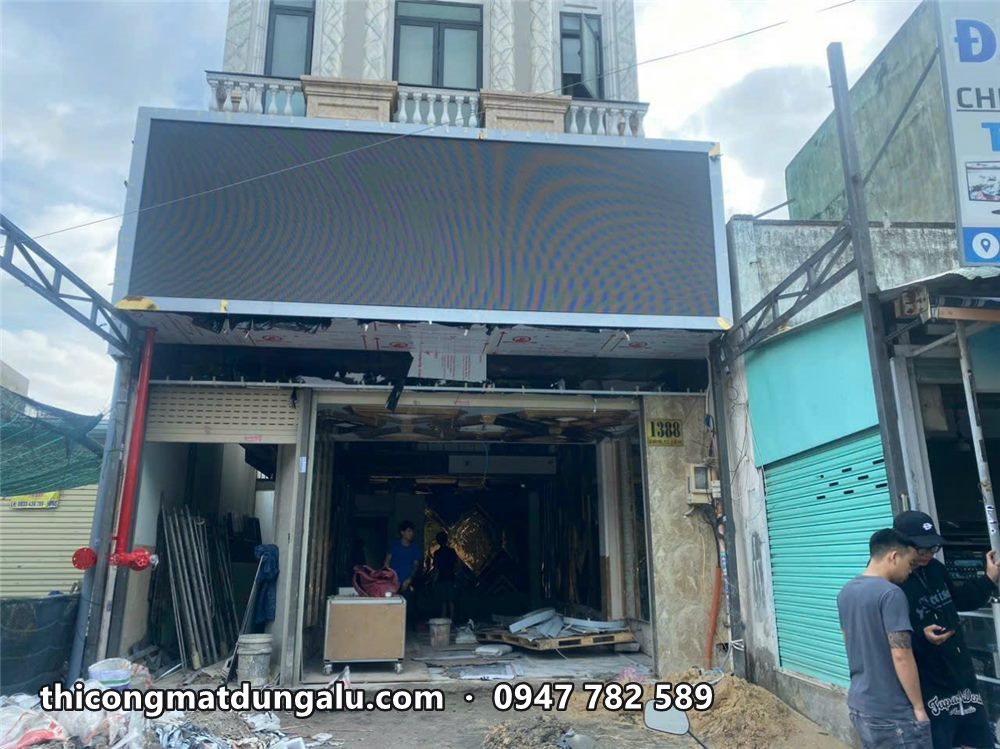 Mặt tiền tầng trệt nhà phố có khung bảng lớn phía trên, cửa hàng đang thi công nội thất