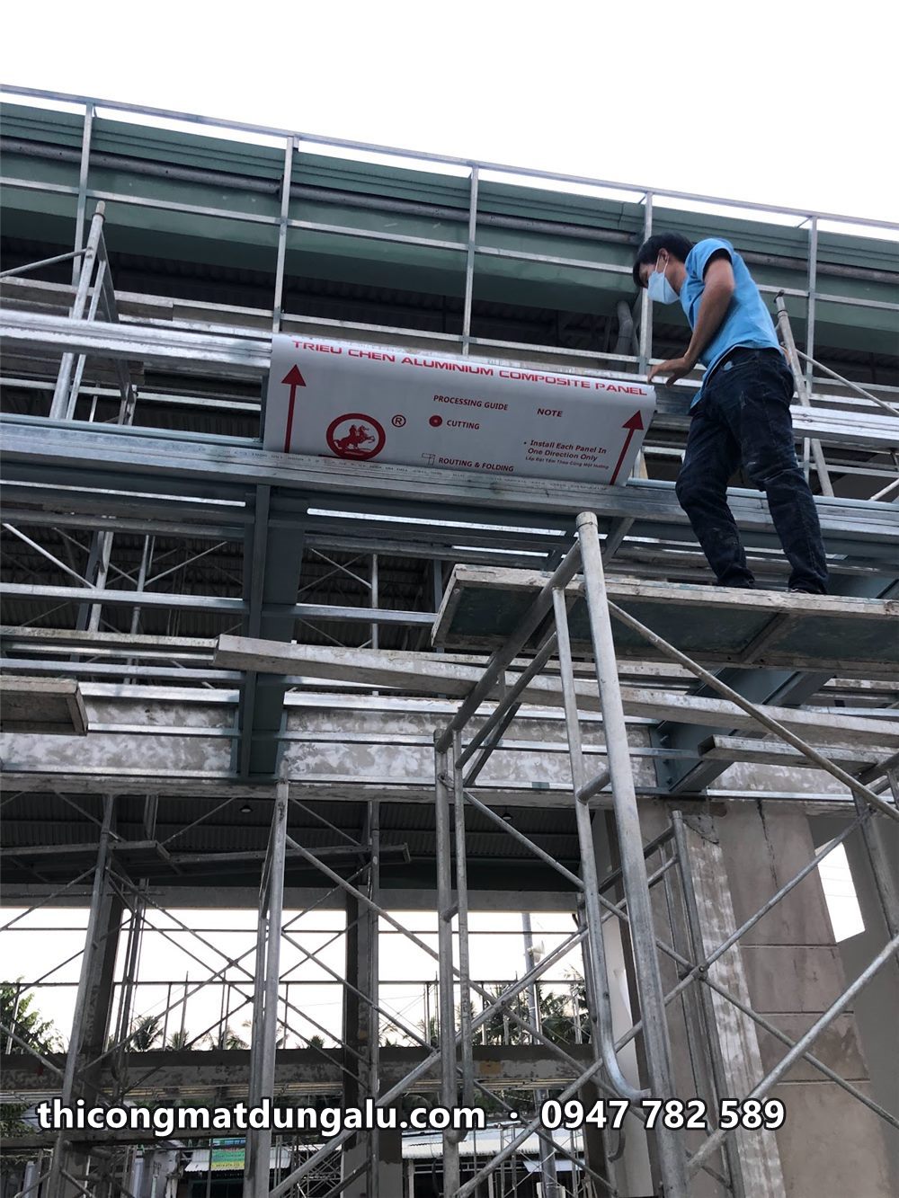 Thợ đứng trên giàn giáo lắp tấm alu lên khung mái đón