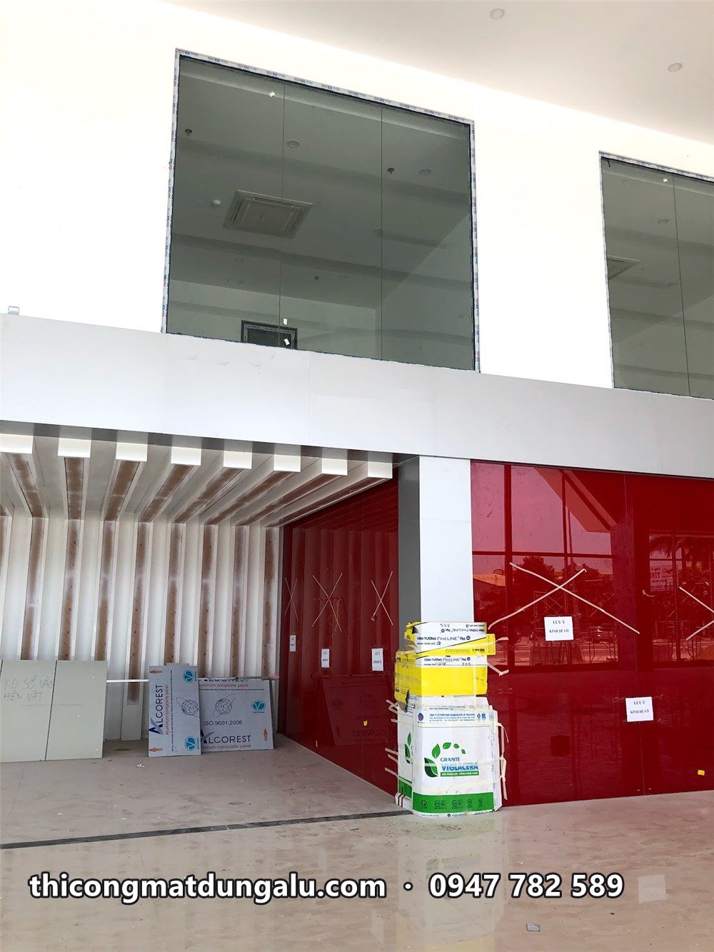 Góc showroom với tường đỏ, lam trắng phía trên và vật tư chất ở góc
