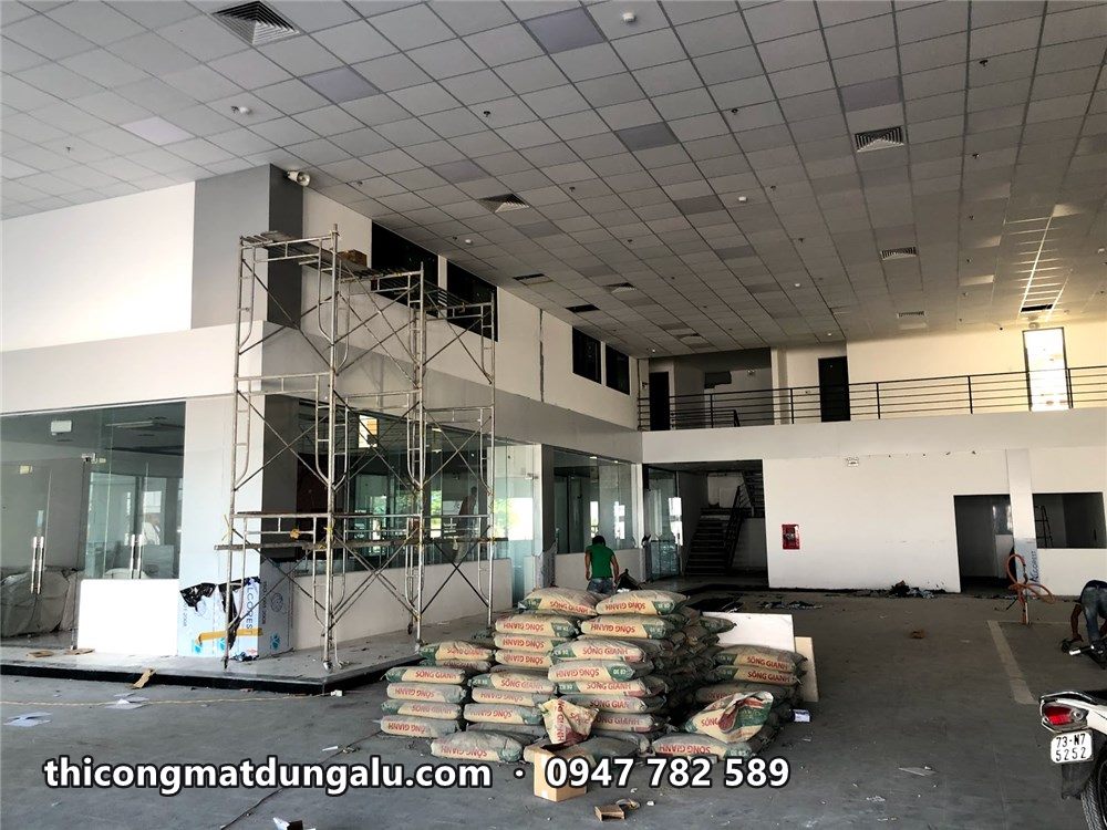 Sảnh showroom gần hoàn thiện, giàn giáo còn ở góc, bao vật tư dưới sàn