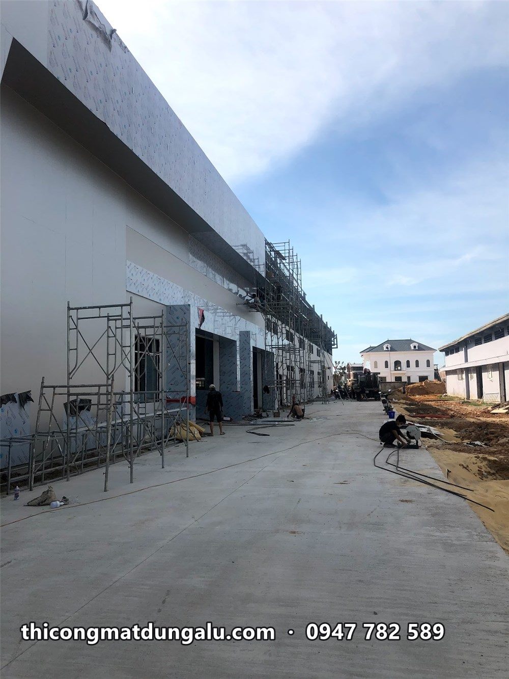 Mặt bên dài của xưởng dịch vụ đang ốp alu, giàn giáo dọc tường