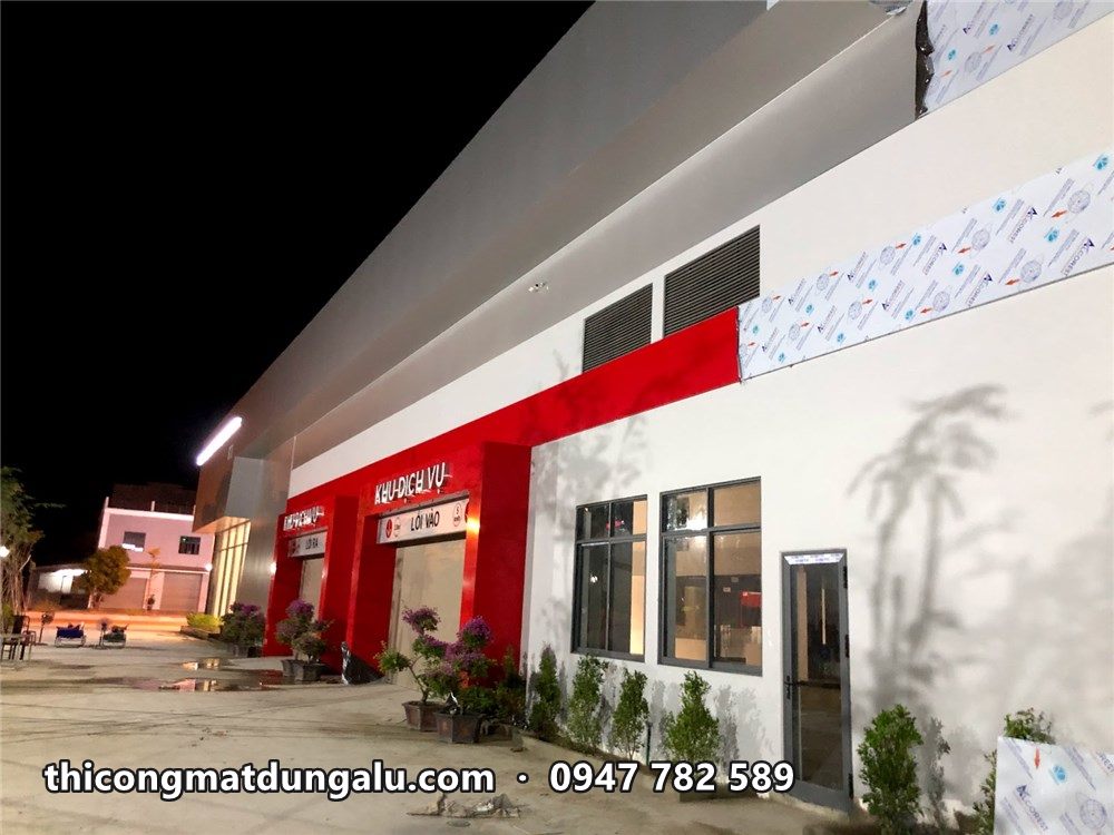 Xưởng dịch vụ VinFast lúc chiều tối, mảng đỏ và trắng đã bóc màng, đèn sáng
