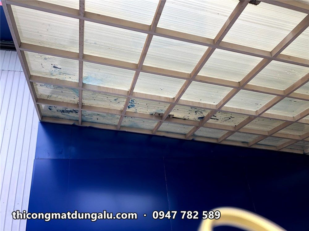 Nhìn lên mái che lấy sáng và mép ốp alu xanh phía trên cửa xưởng