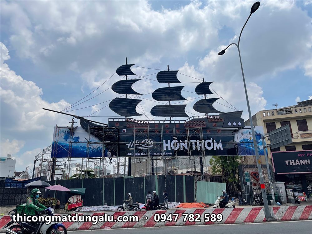 Pano Hồn Thơm với mô hình thuyền ba cánh buồm đen khổng lồ phía trên, xe máy chạy phía dưới