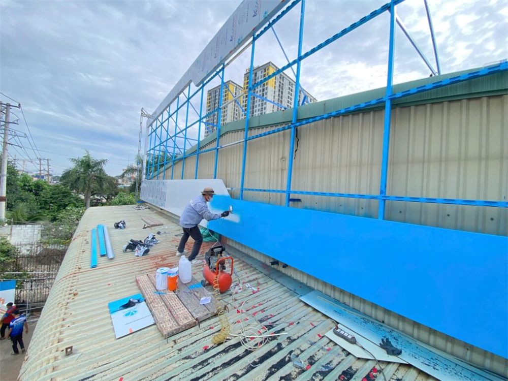 Thợ dán và hoàn thiện mặt pano xanh trên mái nhà xưởng