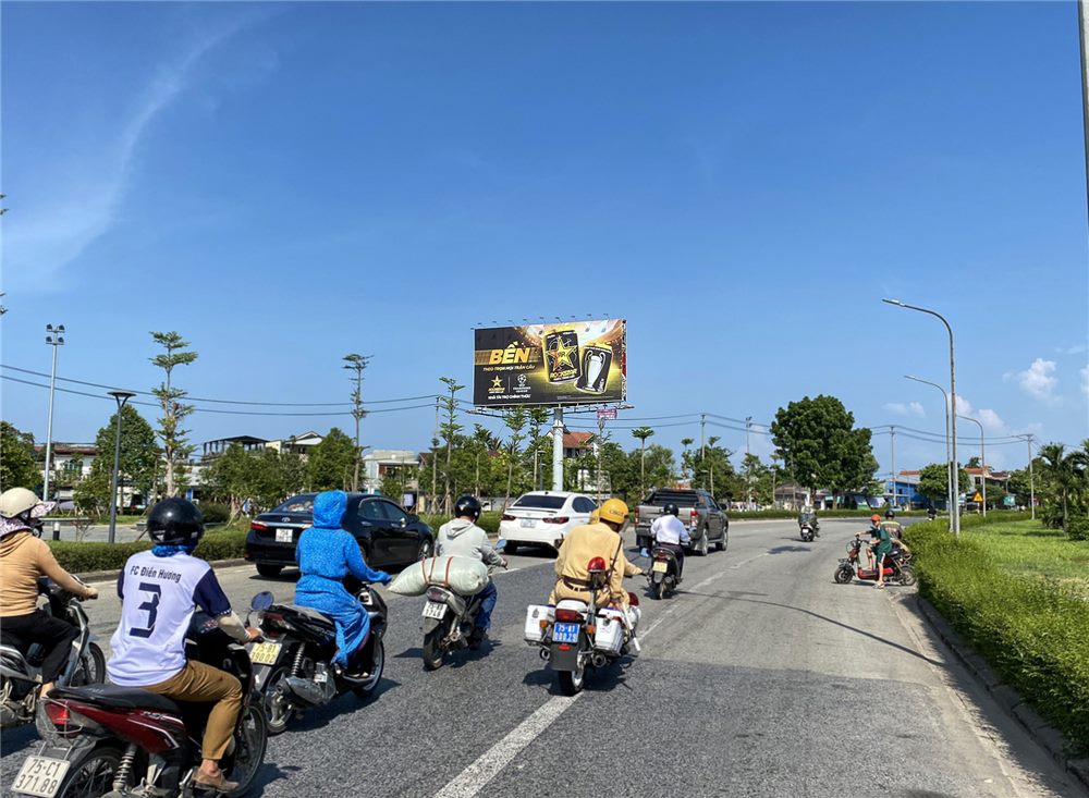 Billboard trên trụ cao bên đường lớn, xe máy chạy phía dưới