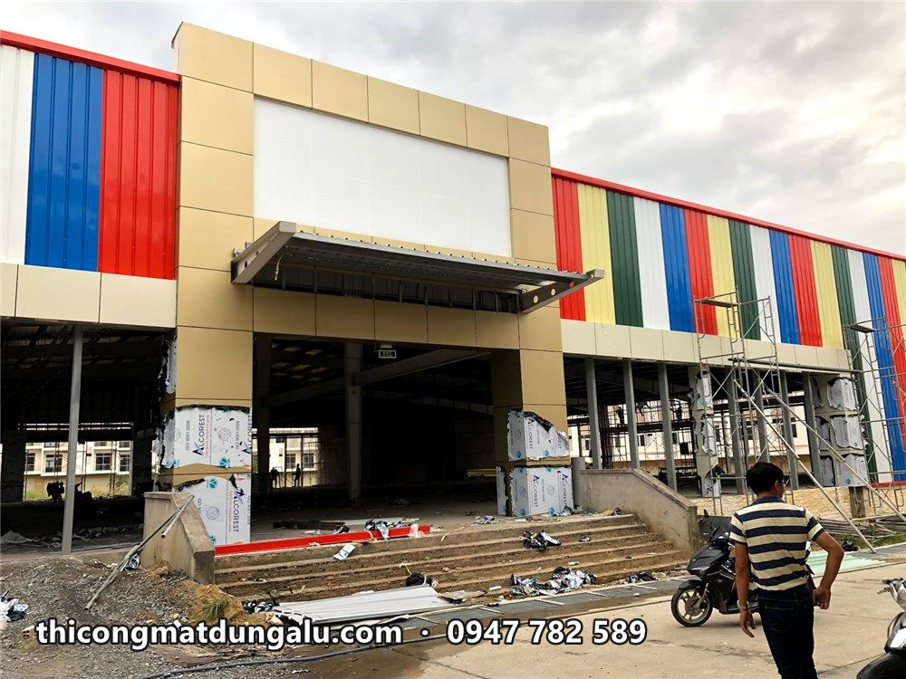 Khối sảnh màu kem với ô biển hiệu trắng và mái đón trên cửa kính