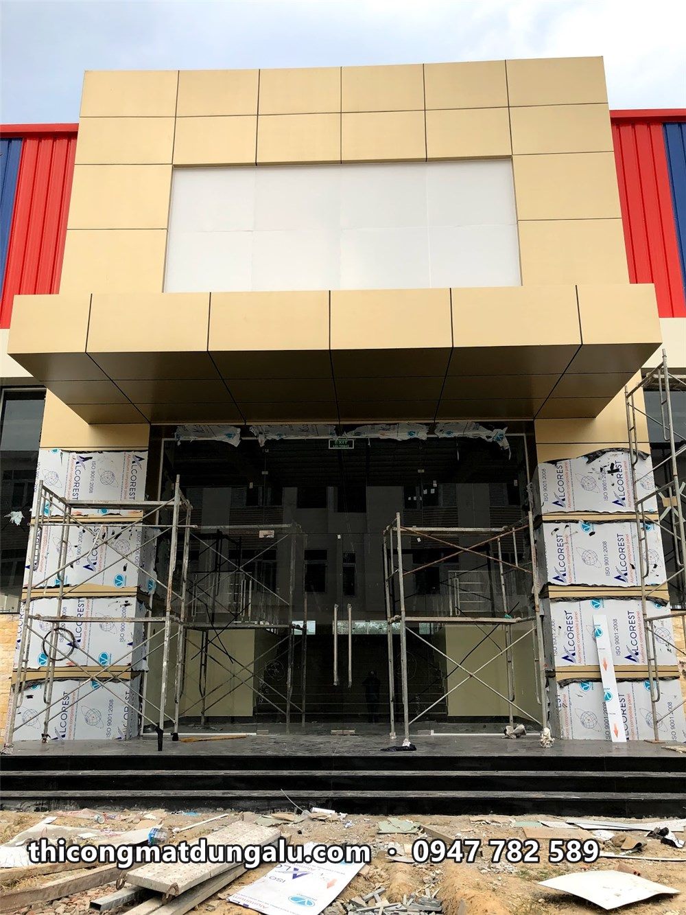 Nhìn thẳng vào khối sảnh, mái đón và cửa kính, chân cột còn tấm chưa bóc màng