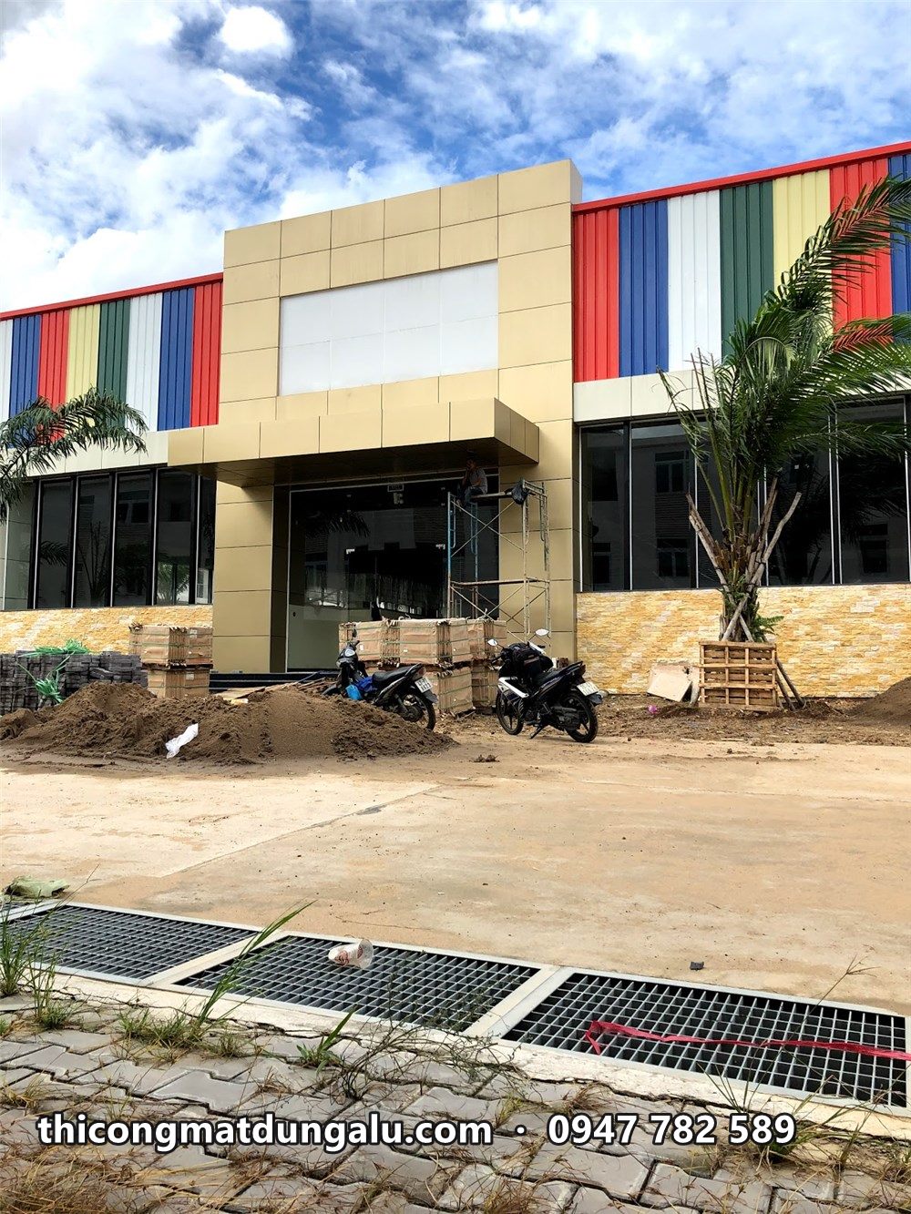 Khối sảnh màu kem giữa mặt dựng sọc màu và cây cau mới trồng