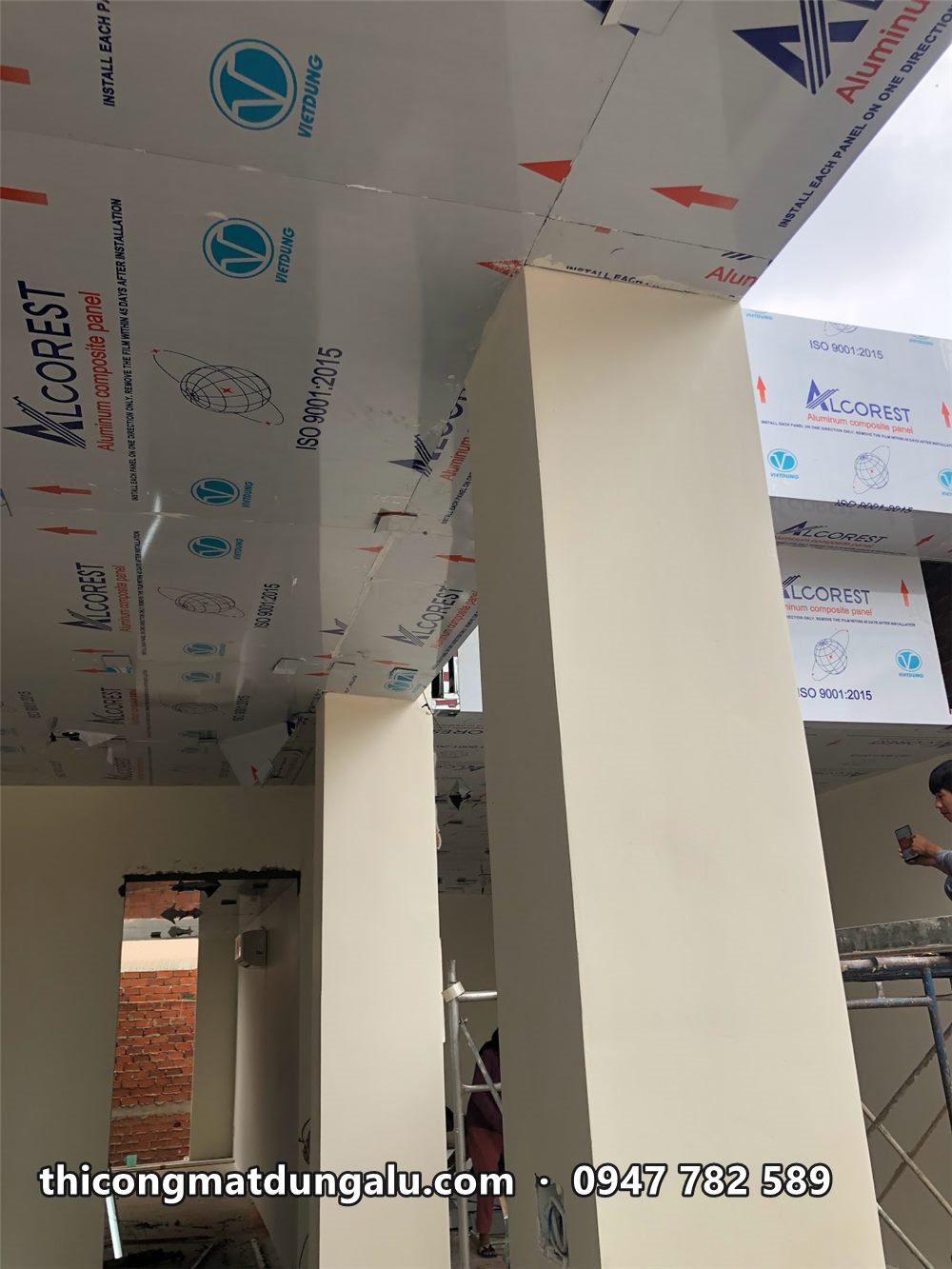 Trần alu còn dán màng bảo vệ Alcorest, cột trắng phía dưới, nhìn từ dưới lên
