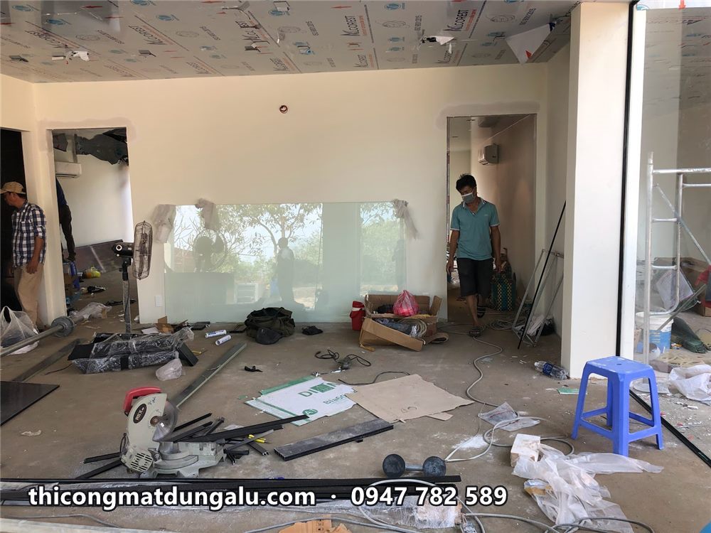Phòng khách nhà vườn với trần alu còn dán màng, thợ đang hoàn thiện bên dưới