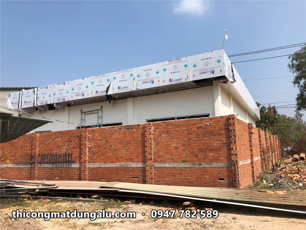 Viền mái nhà vườn đang ốp tấm alu còn dán màng, nhìn từ ngoài tường rào gạch