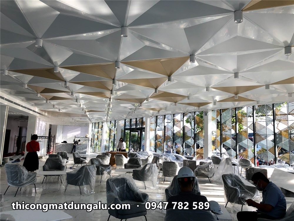 Sảnh nhà mẫu với trần tam giác trắng vàng, ghế sofa xám đang bày