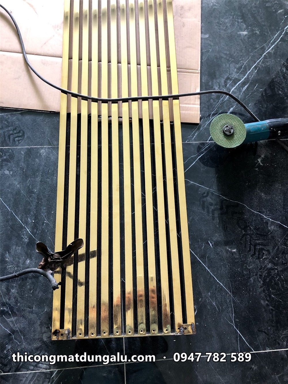 Các thanh inox vàng gương dài xếp trên sàn trước khi lắp